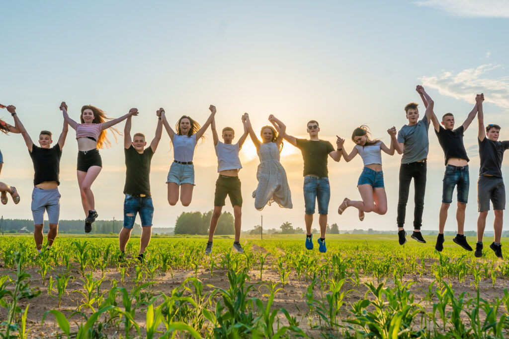 Friends are jumping holding hands at sunset.